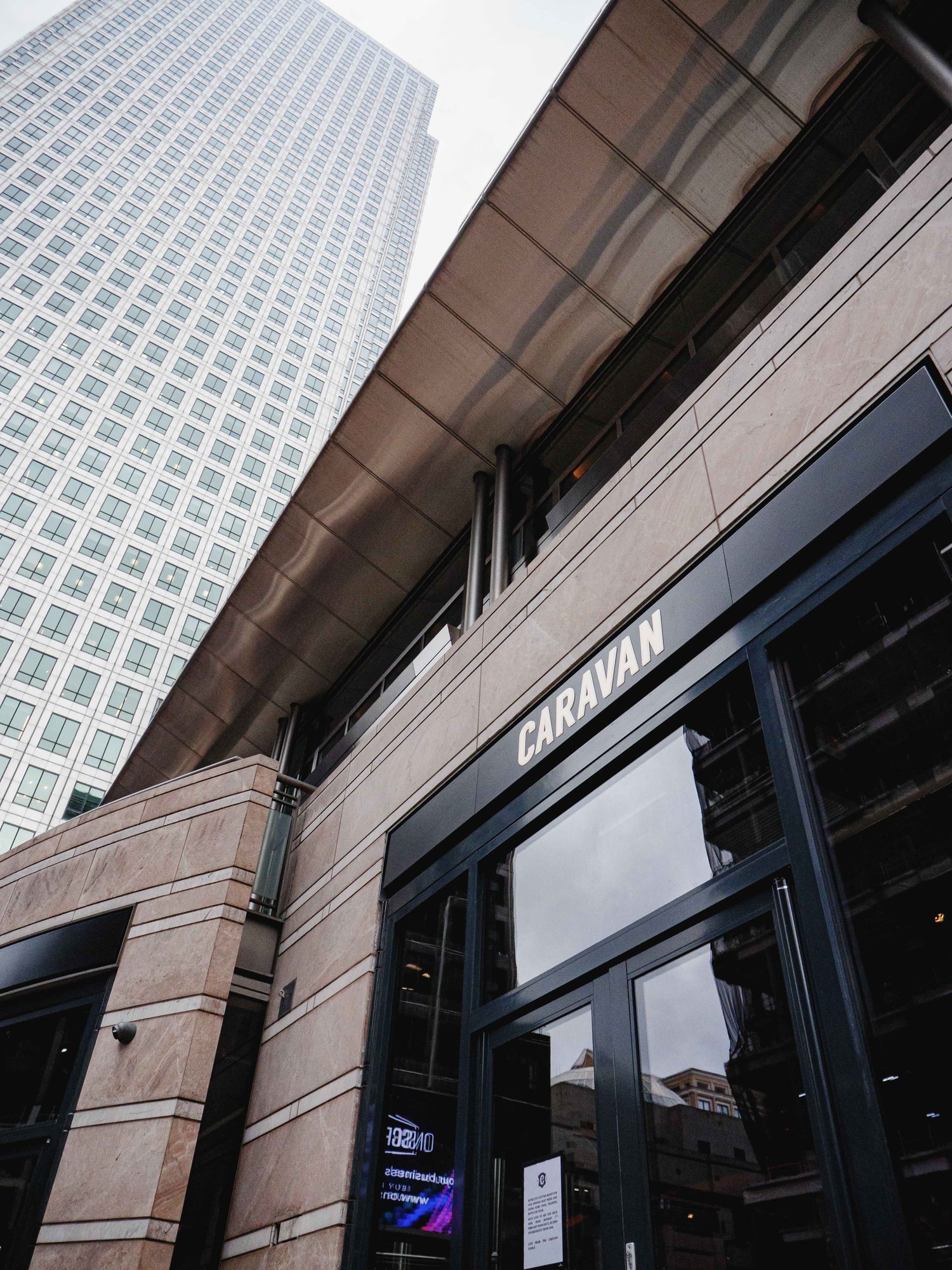Building exterior with 'CARAVAN' sign and skyscraper in the background