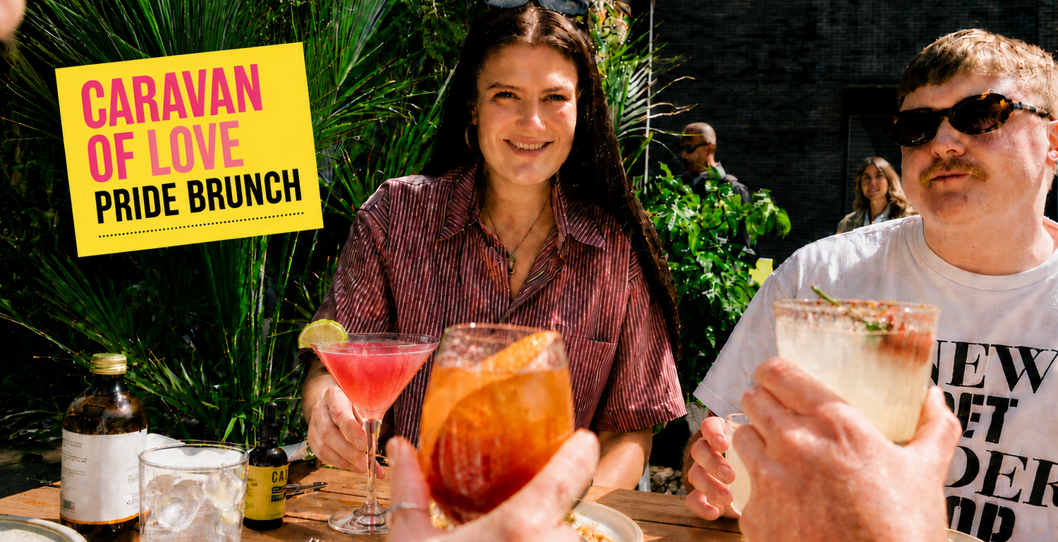 Two people enjoying drinks at a Pride brunch event with a 'Caravan of Love' sign in the background.